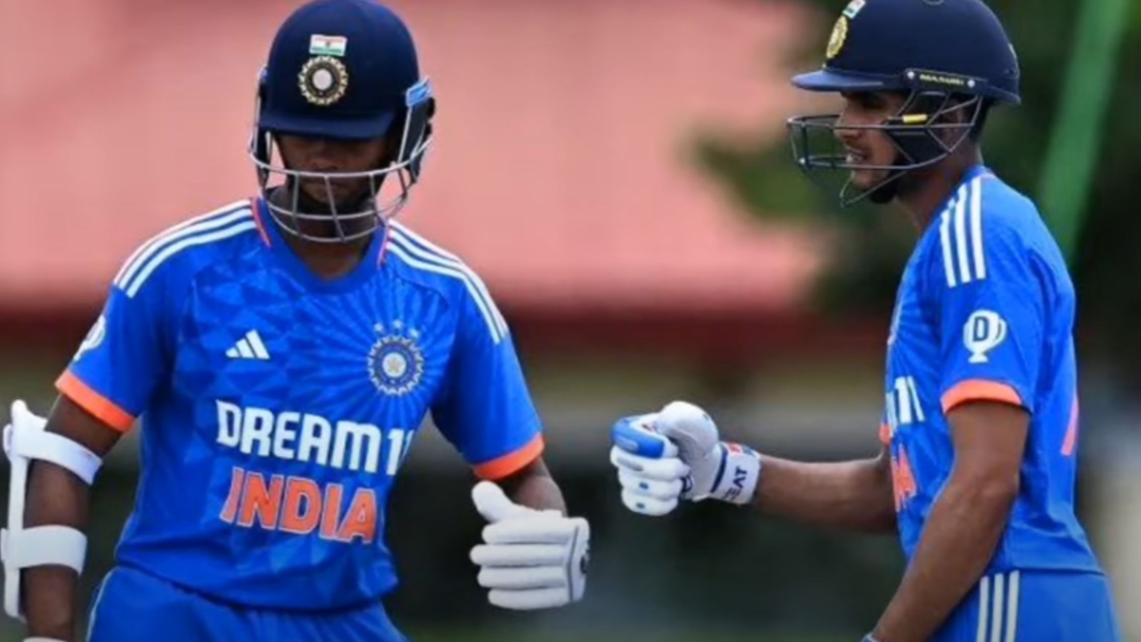 Cricketers Yashasvi Jaiswal and Shubman Gill shaking hands on the cricket field.